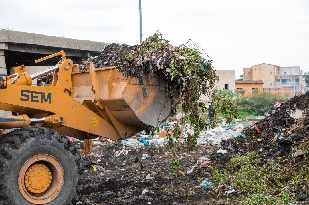 Pelleteuse déblayant les déchets dans un site urbain à N'Djaména.